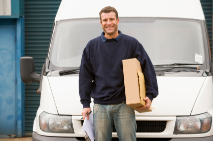Deliveryperson standing with van holding clipboard 