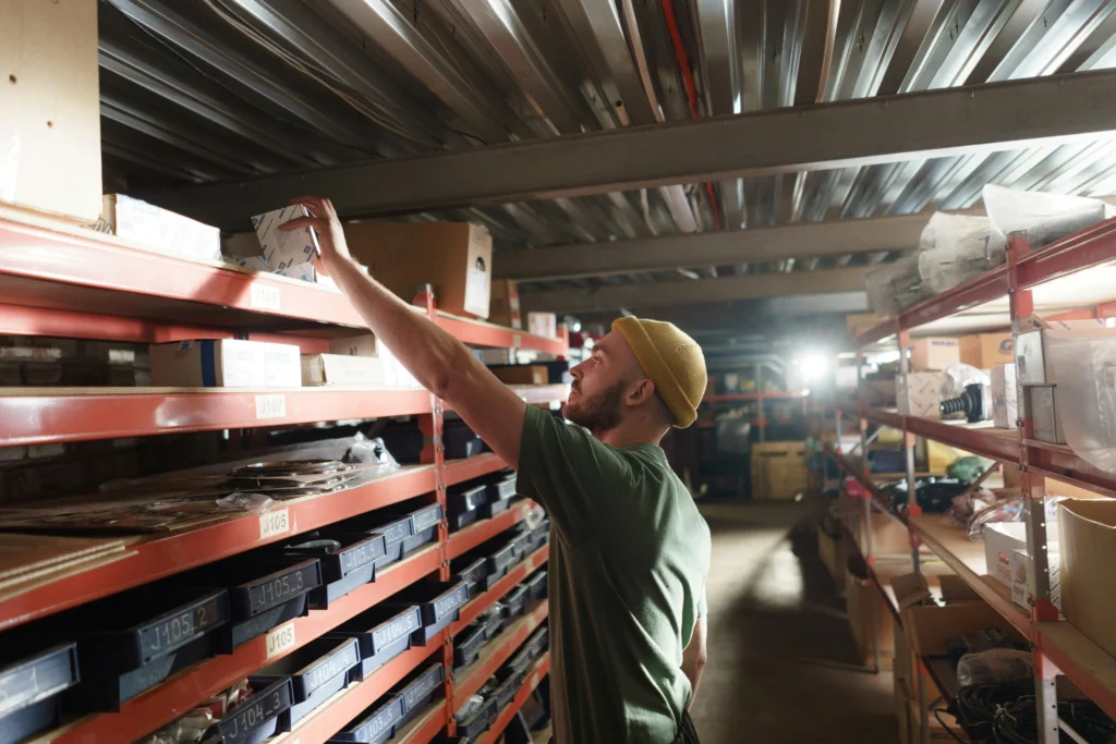 A man holding a small box in a storeroom: saving warehouse space 