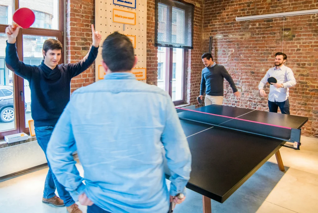 employees playing table tennis in new office