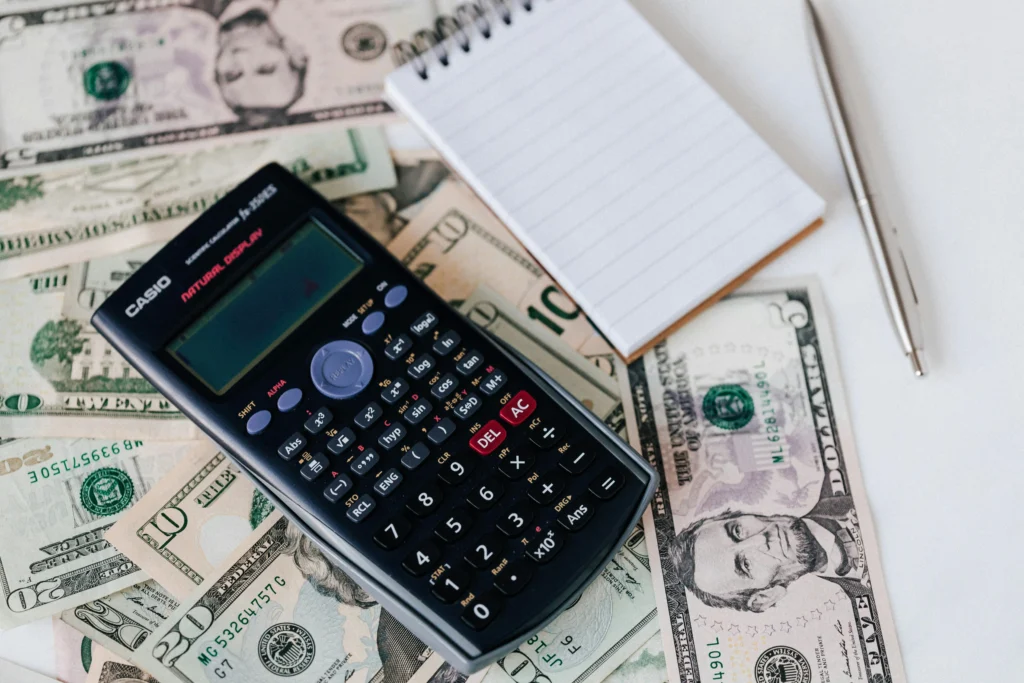 sources of funds: A calculator with a notebook and a pen and stack of money