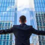 successful man in suit embracing skyscrapers